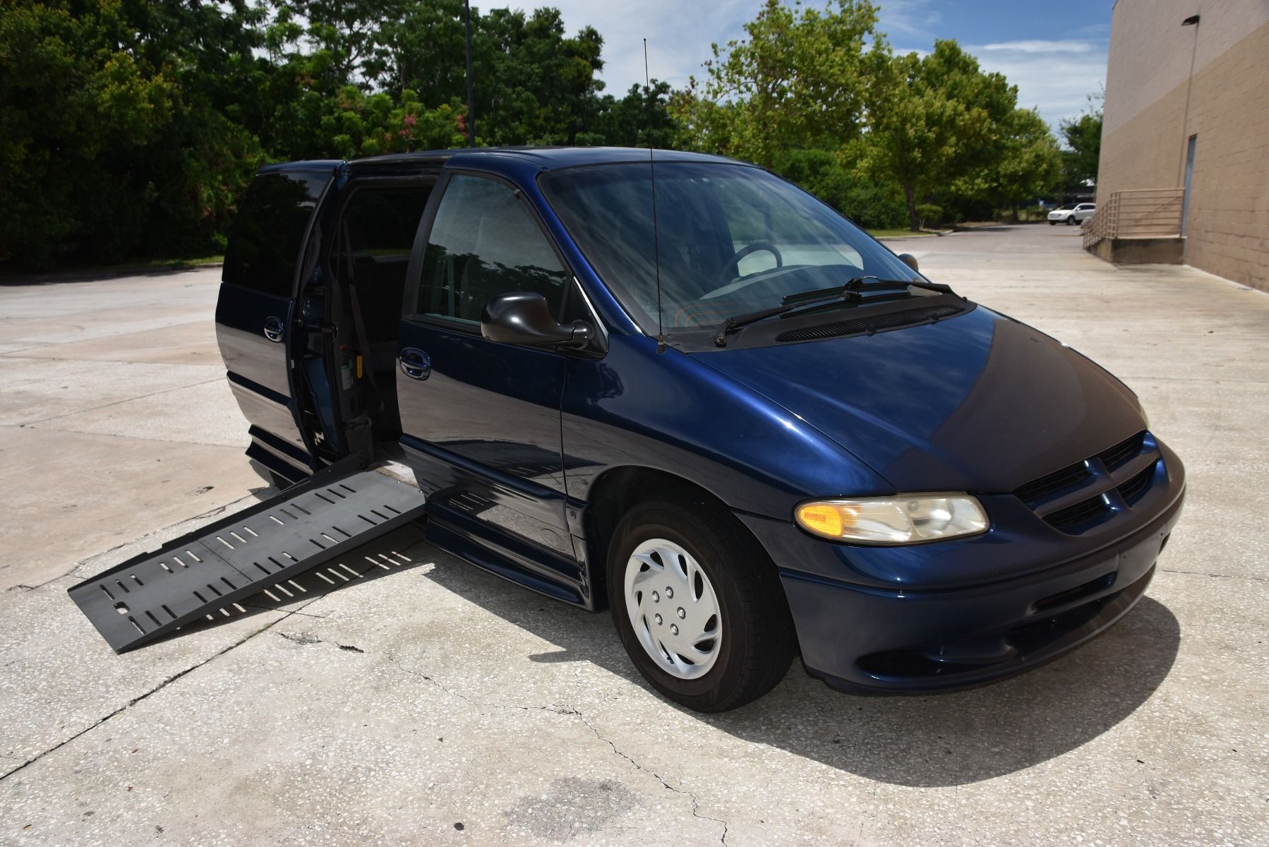 Passenger Side of a Blue Dodge Grand Caravan Wheelchair Van with ramp deployed, as seen from front angle.