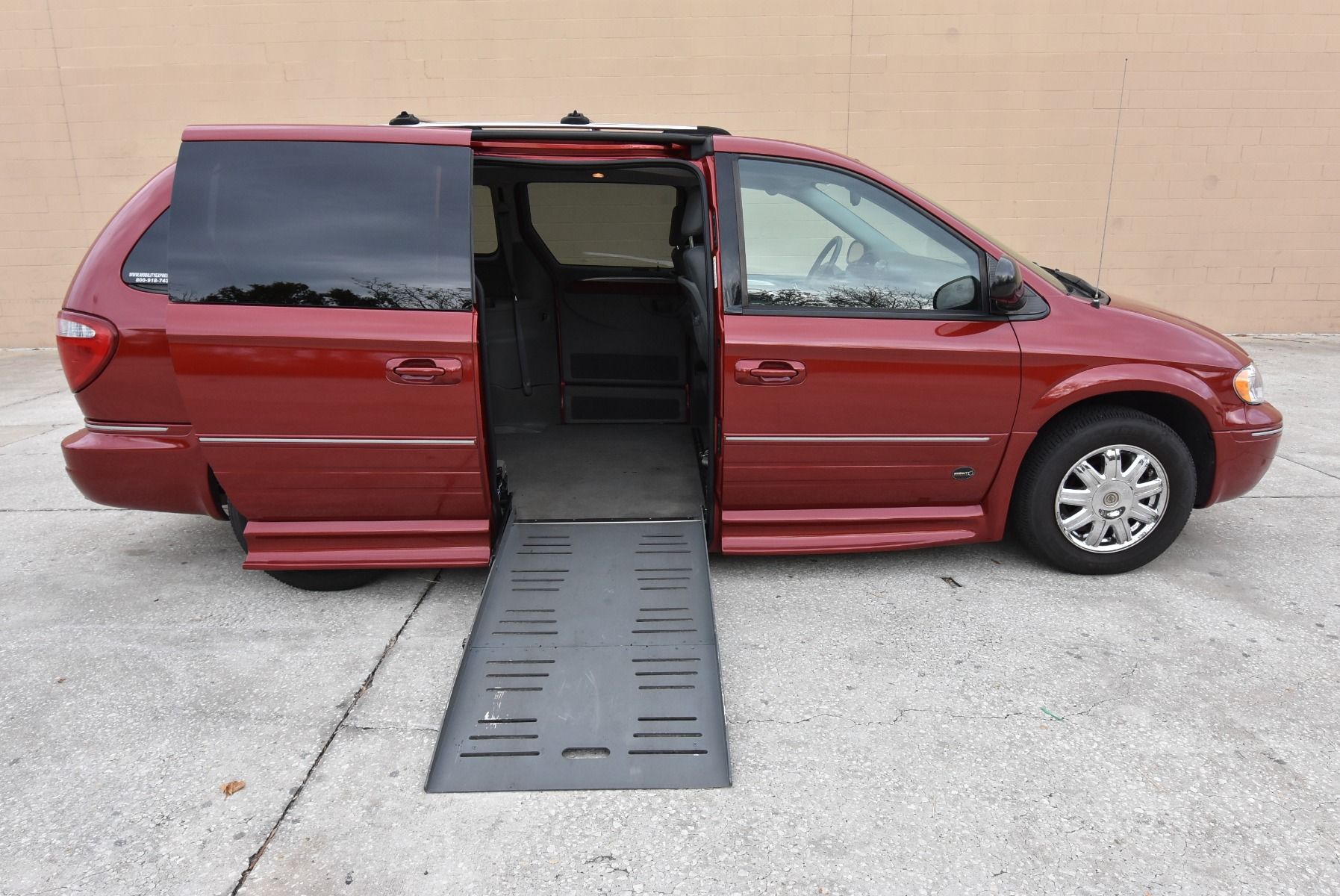 Red 2005 Chrysler Town & Country wheelchair van with ramp deployed from passenger sliding door.