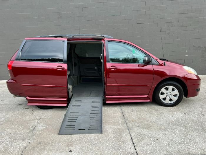 Red 2010 Toyota Sienna wheelchair van parked with the sliding door open and ramp deployed.