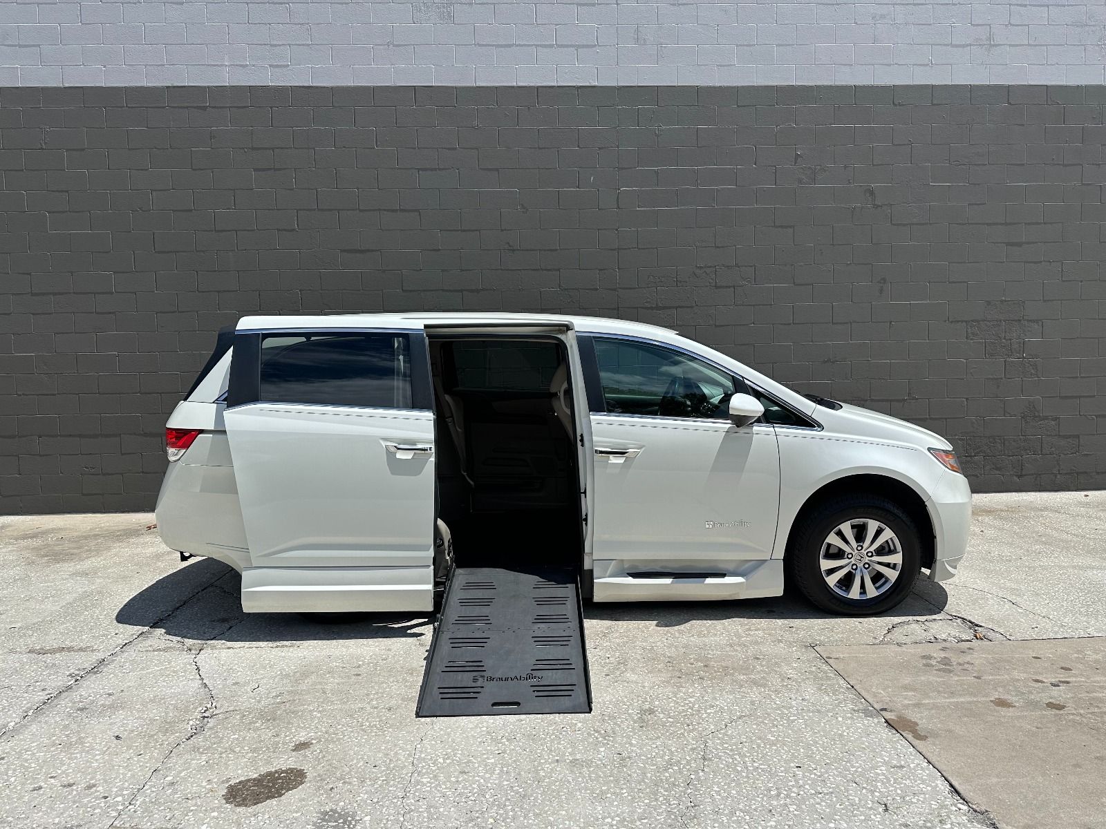 White Honda Odyssey wheelchair van with the ramp deployed from the open passenger side sliding door.