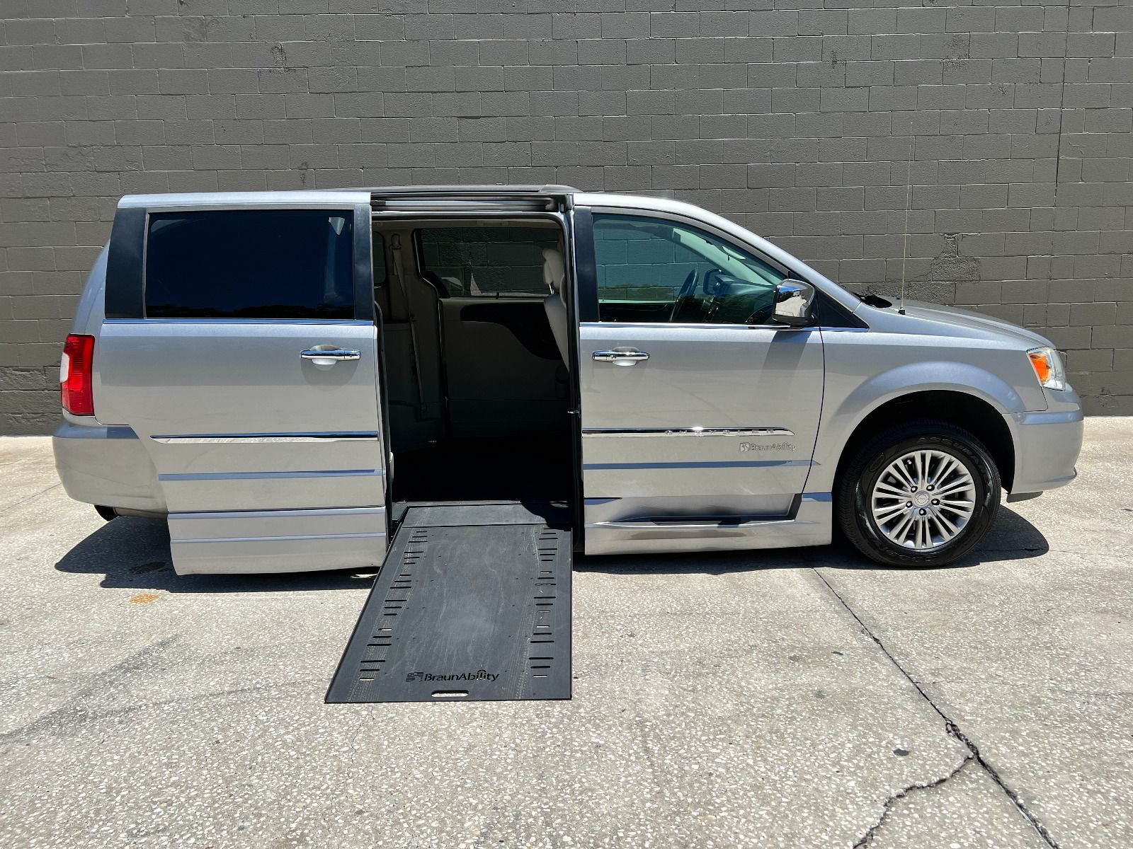 Silver 2016 Chrysler Town & Country wheelchair van with ramp deployed from passenger sliding door.