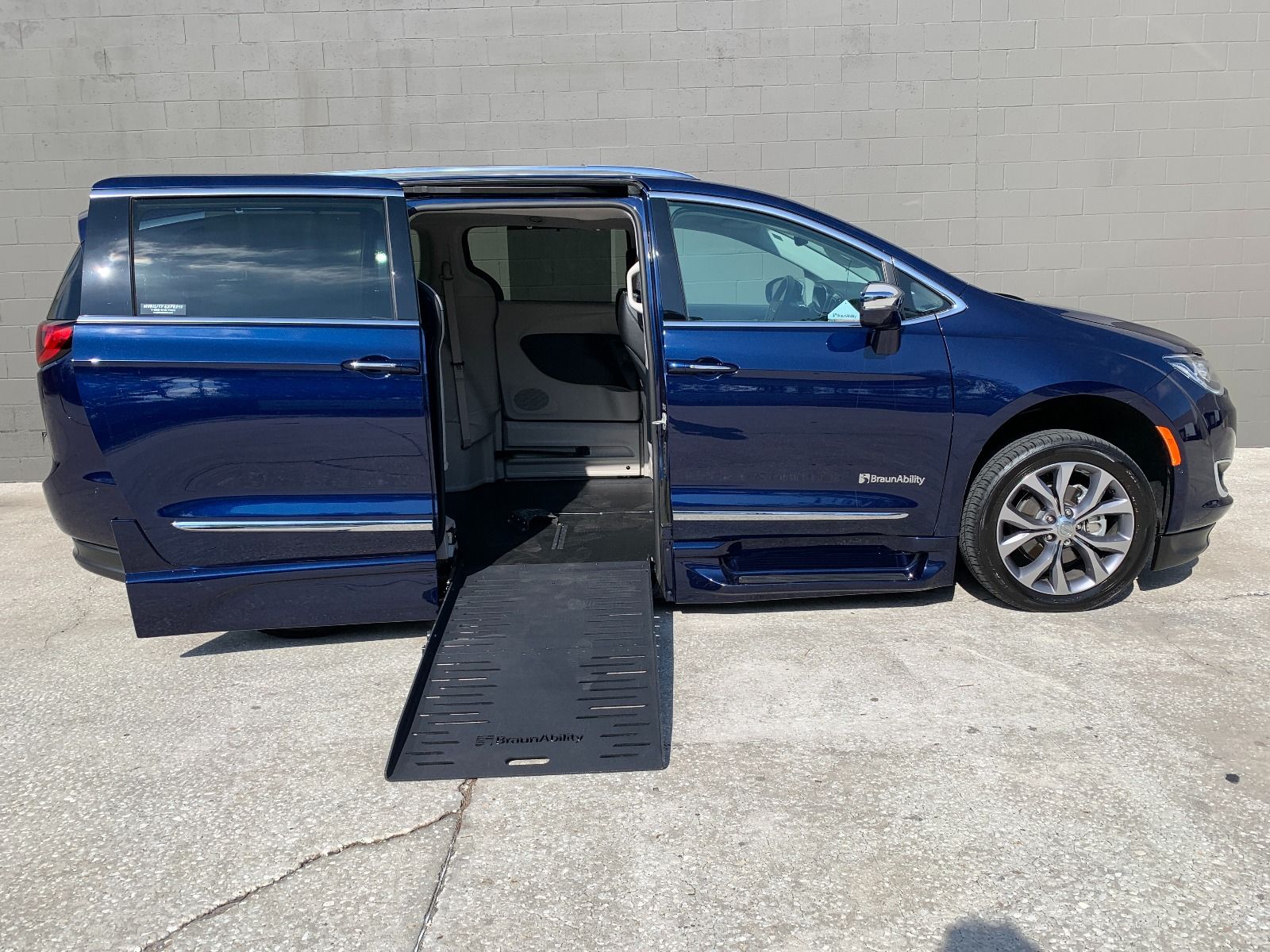 Blue Chrysler Pacifica wheelchair van with ramp deployed from passenger sliding door.