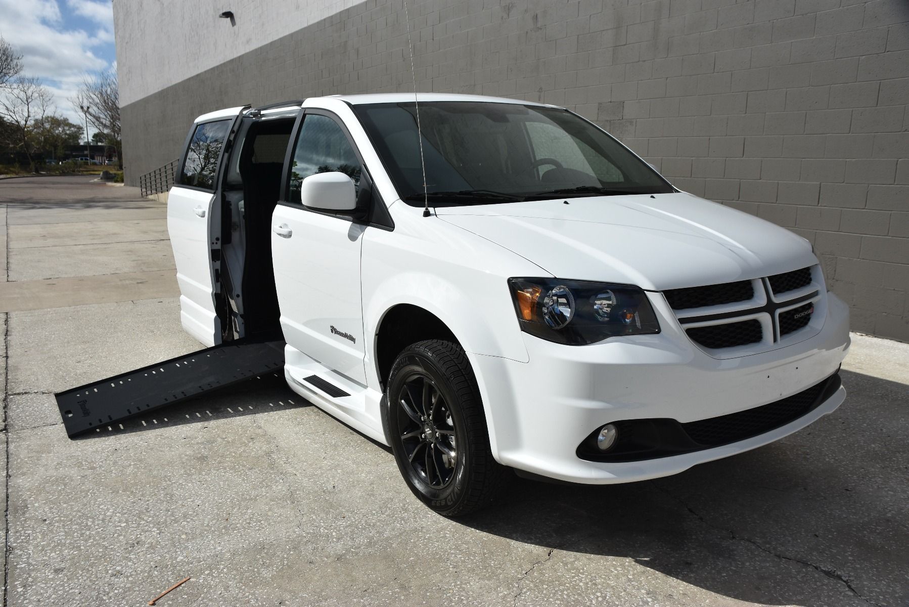 White 2020 Dodge Grand Caravan Wheelchair Van with ramp deployed, as seen from passenger side front angle.
