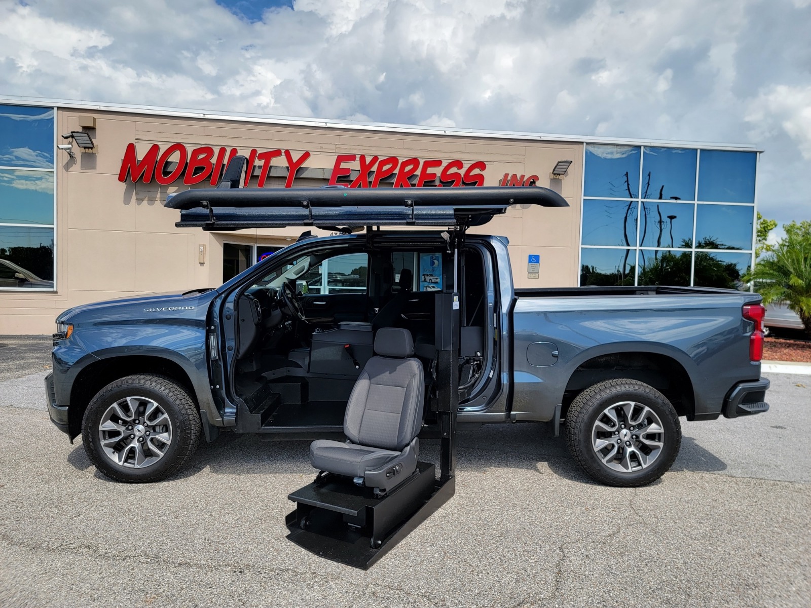 Red Chevrolet Traverse wheelchair accessible suv with ramp deployed from open passenger side rear door.