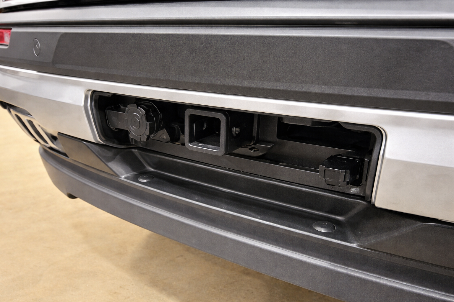 The rear bumber of a wheelchair accessible Chevrolet Traverse. There is a cutout section of the bumper removed, and the exposed area shows a hitch receiver.