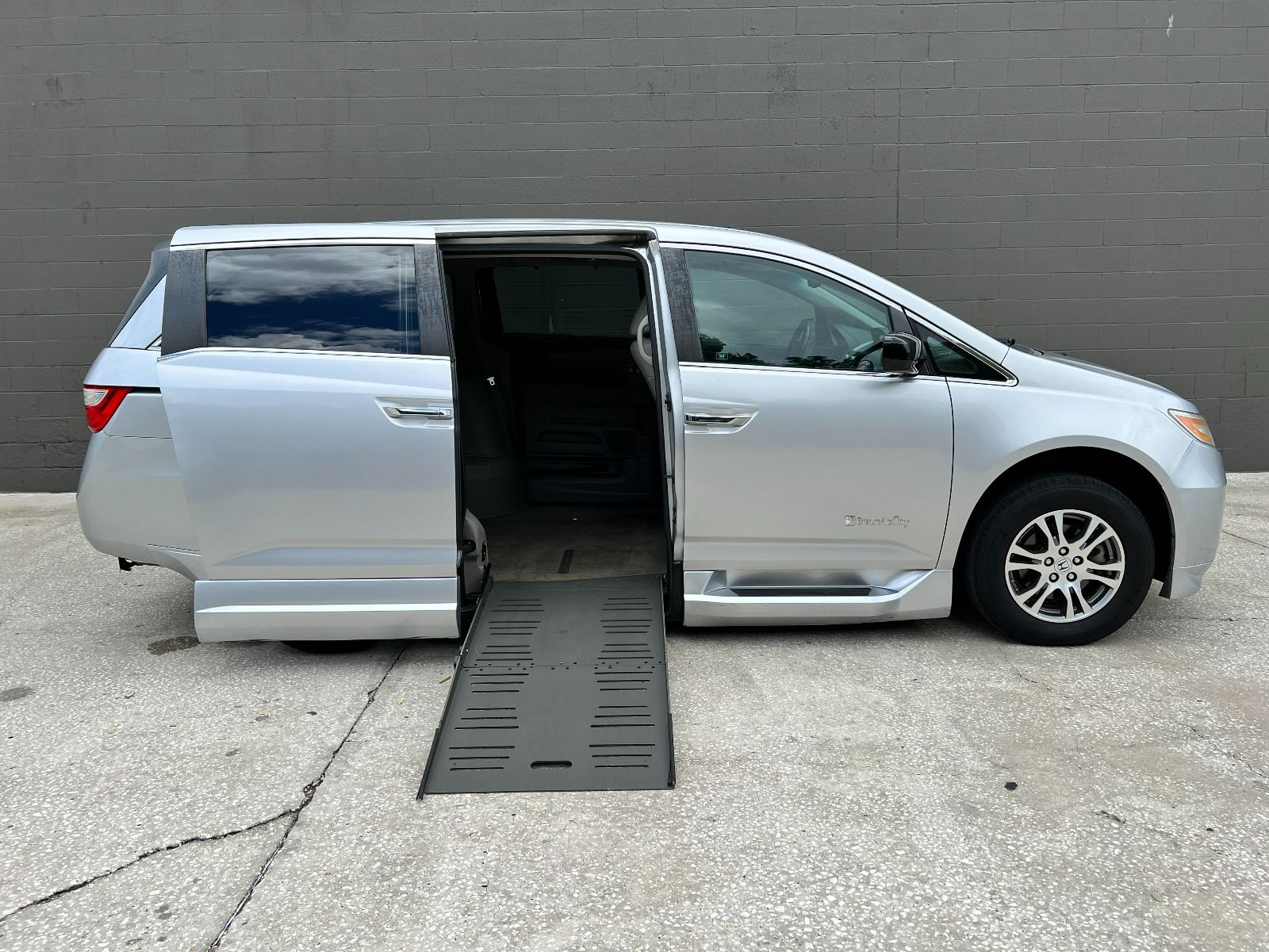 Passenger side of a silver 2012 Honda Odyssey Wheelchair Van, with ramp deployed