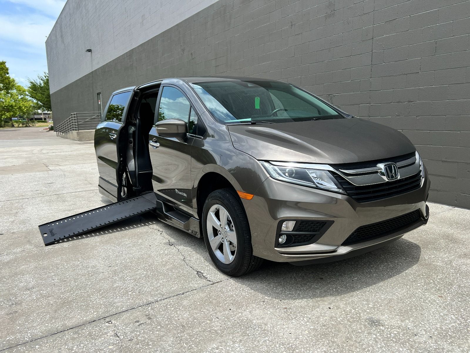 Gray 2019 Honda Odyssey Wheelchair Van with ramp deployed, as seen from passenger side front angle.