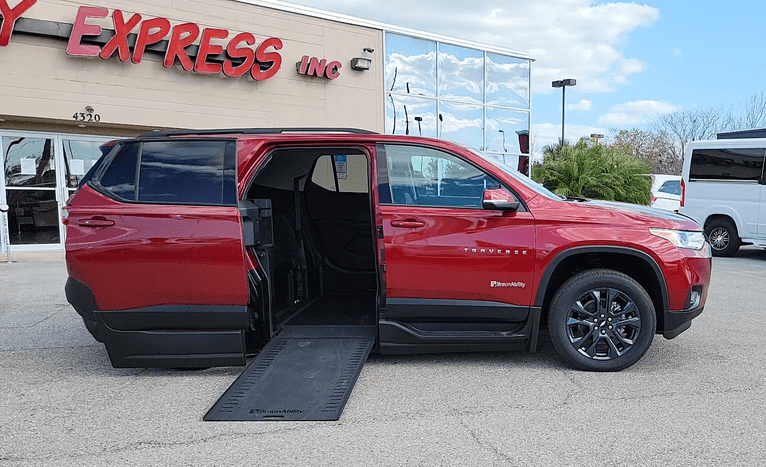 Red Chevrolet Traverse wheelchair accessible suv with ramp deployed from open passenger side rear door.