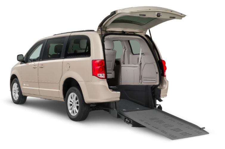 A sand colored Dodge Grand Caravan with BraunAbility Rear Entry Conversion with the ramp deployed from the rear hatch.