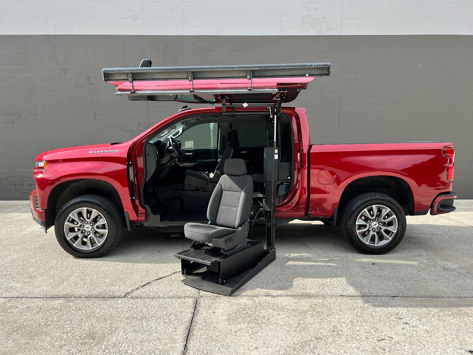 Silver Chevrolet Traverse wheelchair accessible suv with ramp deployed from open passenger side rear door.