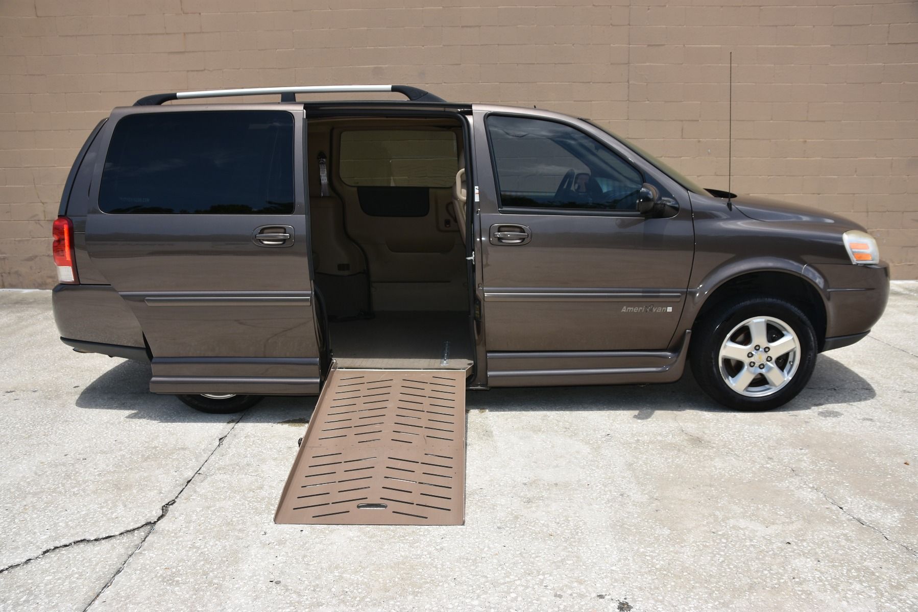 Brown Chevrolet Uplander Wheelchair Van with ramp deployed from passenger side sliding doorway.