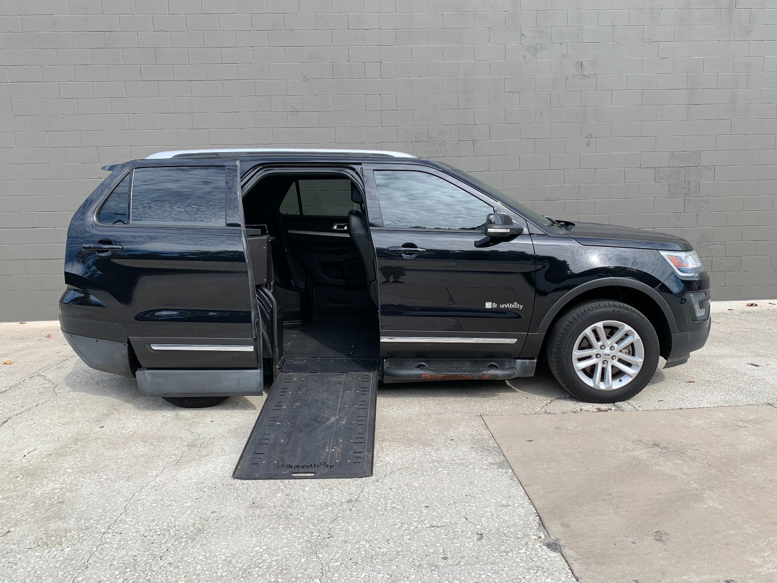 Black Ford Explorer wheelchair accessible SUV with the ramp deployed from the open passenger side rear door.