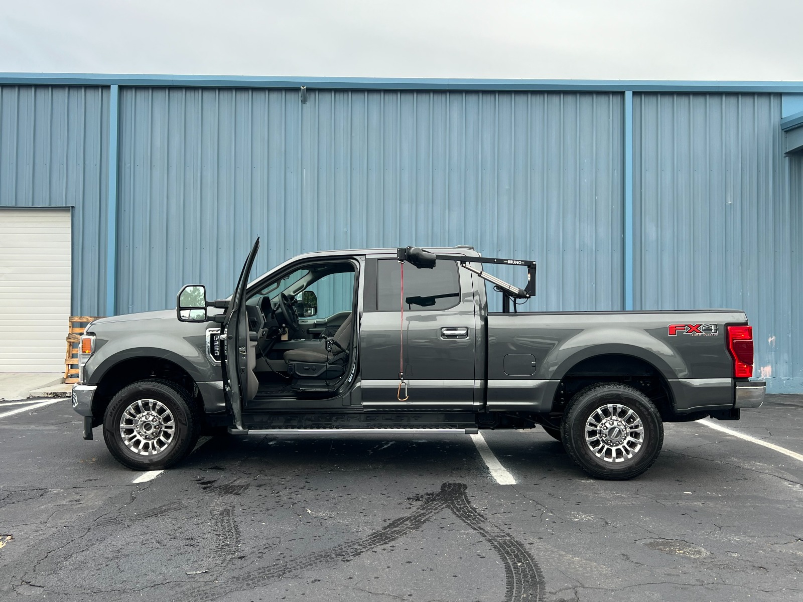 Silver Ford Explorer wheelchair accessible SUV with the ramp deployed from the open passenger side rear door.