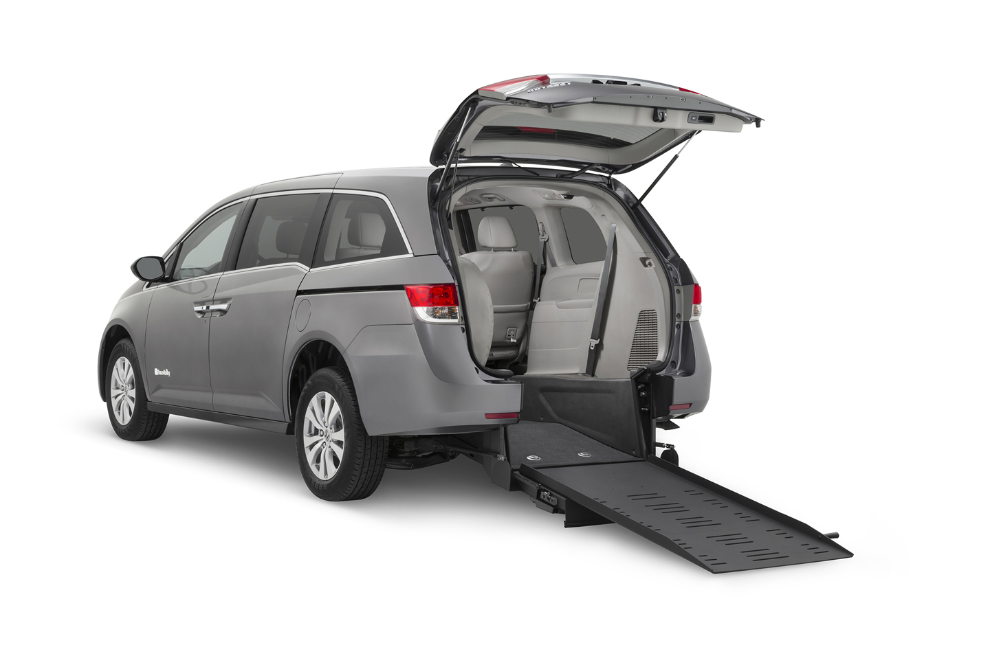 Gray Honda Odyssey with rear entry wheelchair van conversione ramp deployed from open rear hatch.