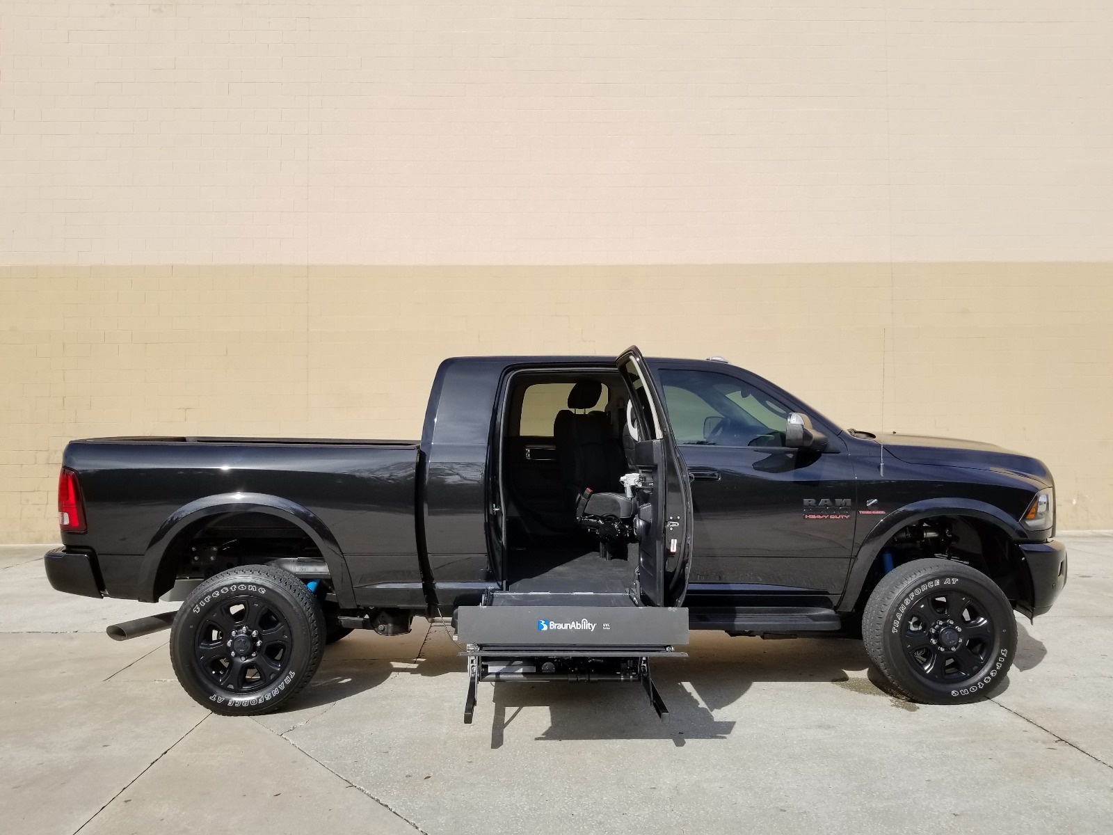 Black RAM 2500 wheelchair accessible truck with lift deployed from open passenger side rear door.