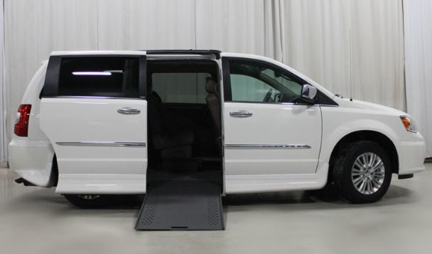 A white Chrysler Town & Country wheelchair van with Rollx conversion with ramp deployed from open passenger sliding door.