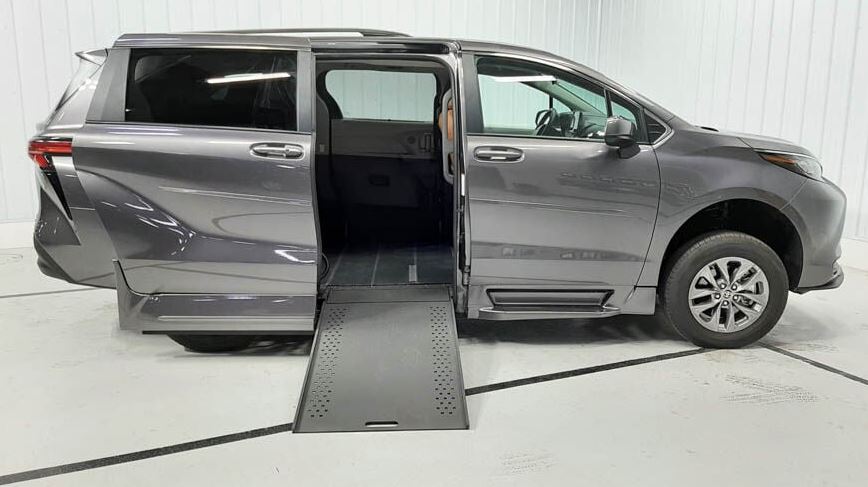 A silver Toyota Sienna Hybrid wheelchair van with Rollx wheelchair van conversion with ramp deployed from open passenger side sliding door.