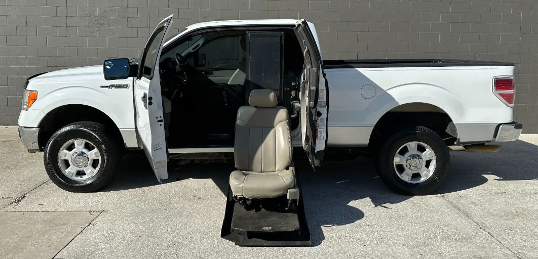 White Ford F-150 Wheelchair Accessible Truck with lift deployed from open driver side doors.