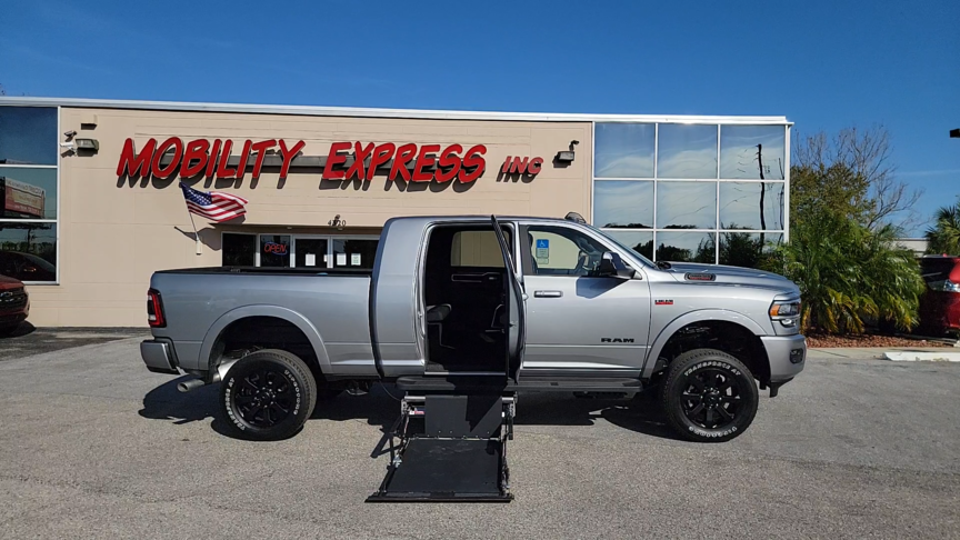 Silver pick up truck with wheelchair lift deployed out of rear passenger door.