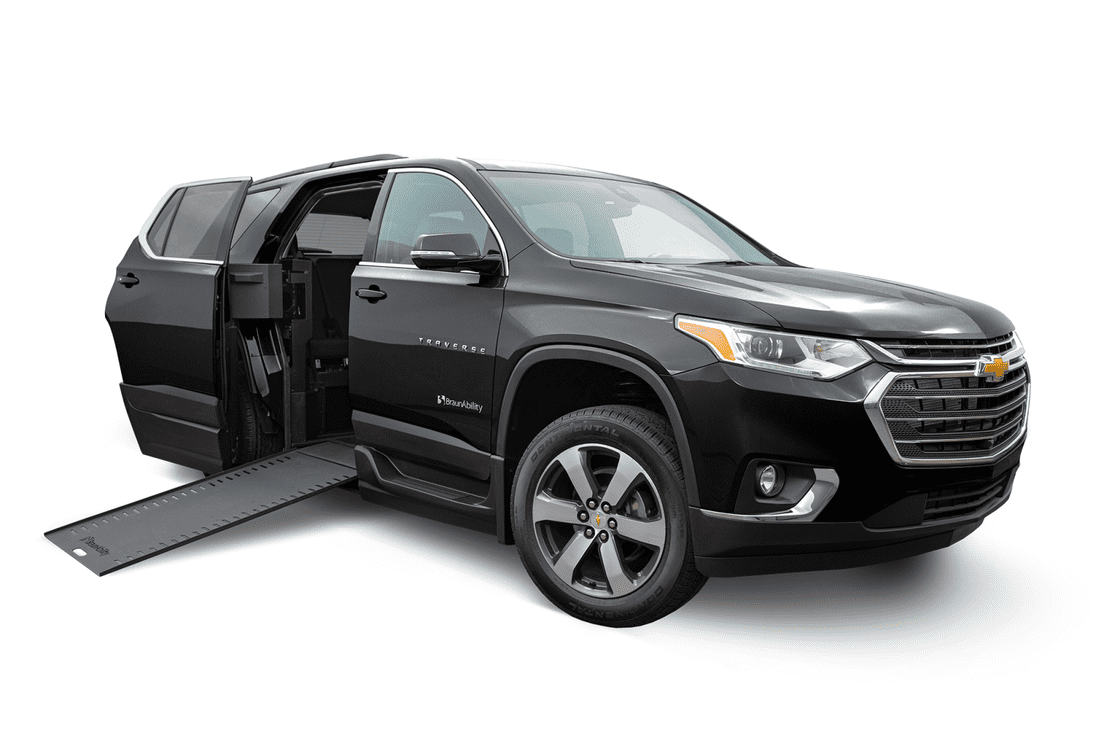 A black, wheelchair accessible Chevrolet Traverse SUV with ramp for wheelchair deployed from passenger side rear door.