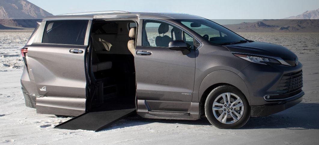 A gray Toyota Sienna Hybrid wheelchair van with VMI Northstar conversion, with the ramp deployed from the passenger sliding doorway.