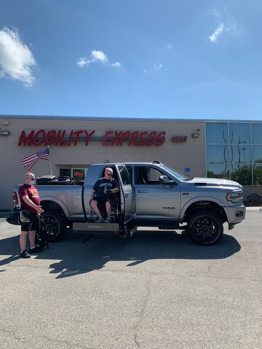 Man in wheelchair getting into truck using wheelchair lift.