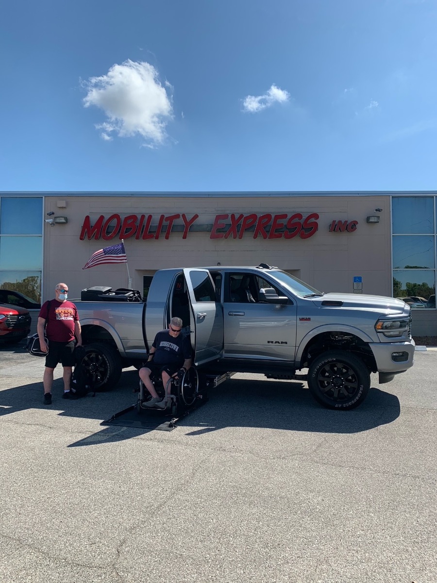 Man in wheelchair using mobility lift to get into a pickup truck,