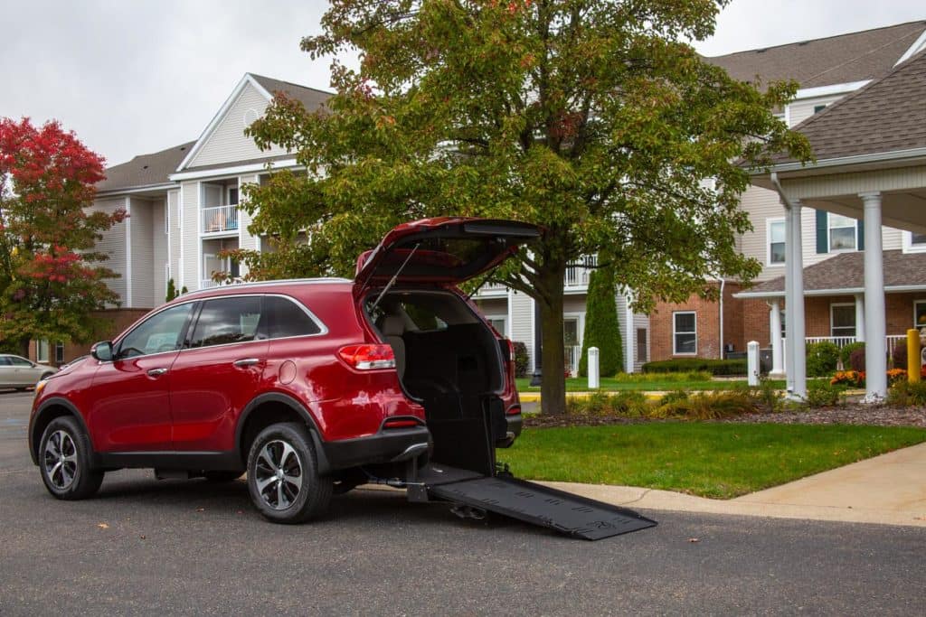 Gray Wheelchair Accessible Kia Sorento SUV with ramp deployed, as seen from passenger side rear angle.