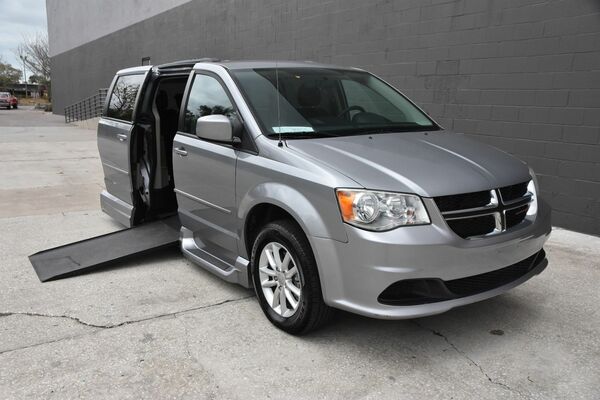 Silver Dodge Grand Caravan that has been converted for wheelchair access, with the ramp deployed.