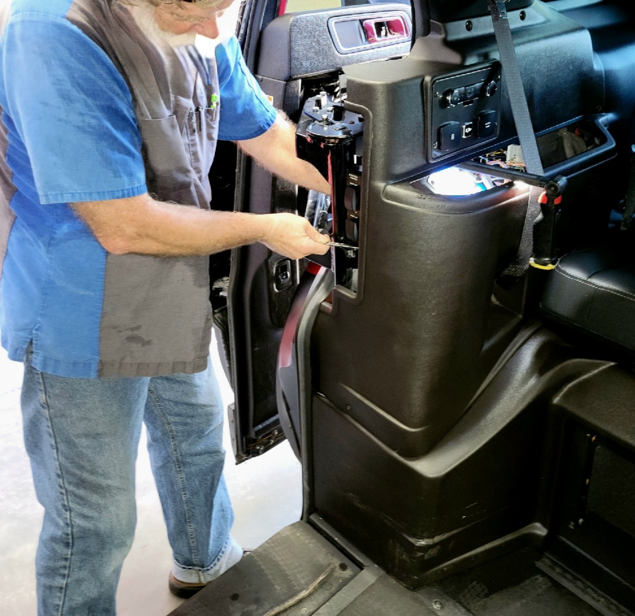 A wheelchair van technician using a wrench to work on a wheelchair accessible van.